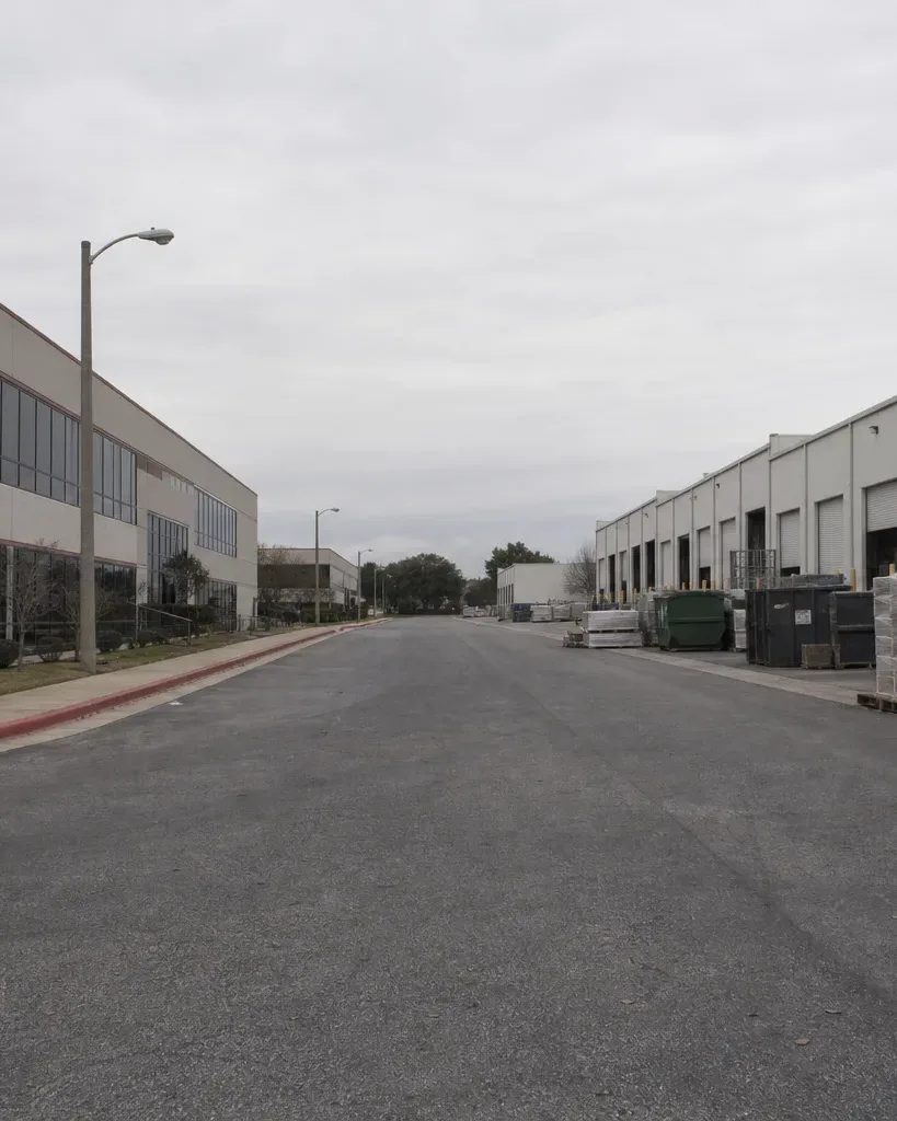 A suburban Austin business-park drive shows a mix of occupied and vacant tilt-wall buildings