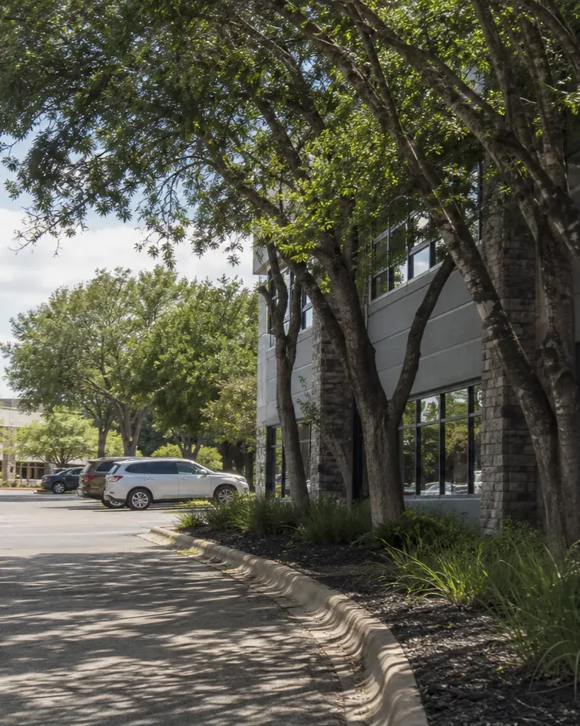 A low-rise suburban Austin office park is seen from the landscaped access drive