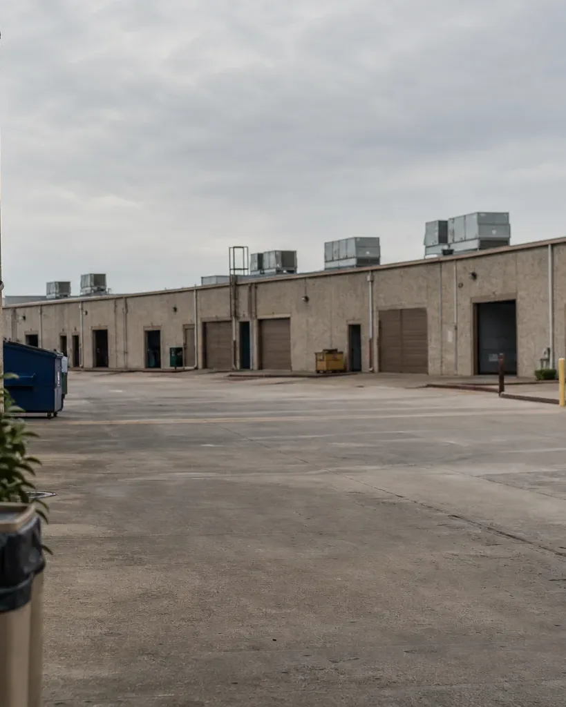 A facilities manager in a hard hat stands on the open industrial floor of a large Austin warehouse