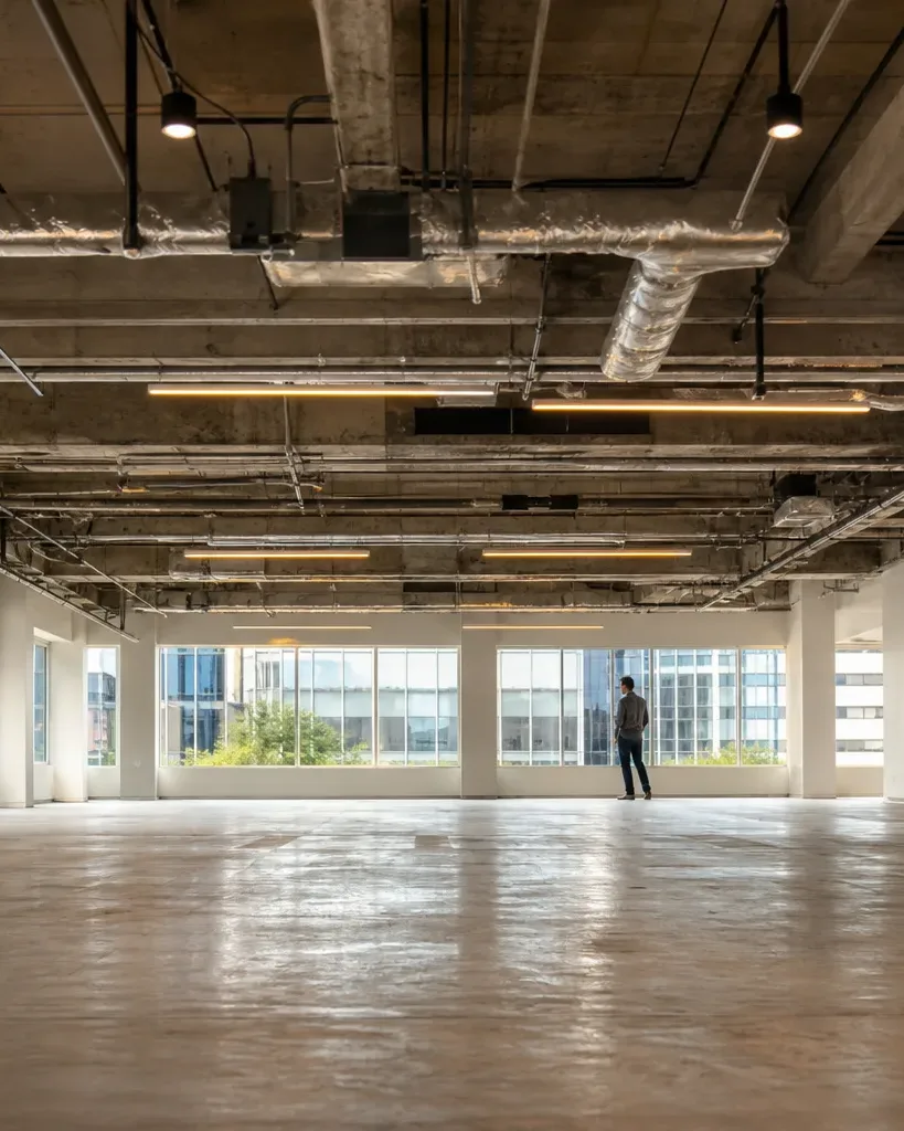 A leasing agent shows a second prospective tenant through a partially improved Austin office suite